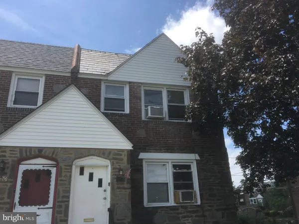 a front view of a house with a tree