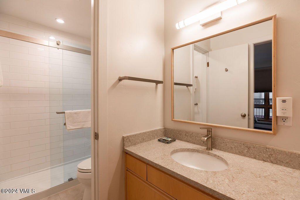 993 Lions Ridge Loop, Unit 343 Vail, CO 81657 - Photo 11 of 15 a bathroom with a granite countertop sink toilet and shower