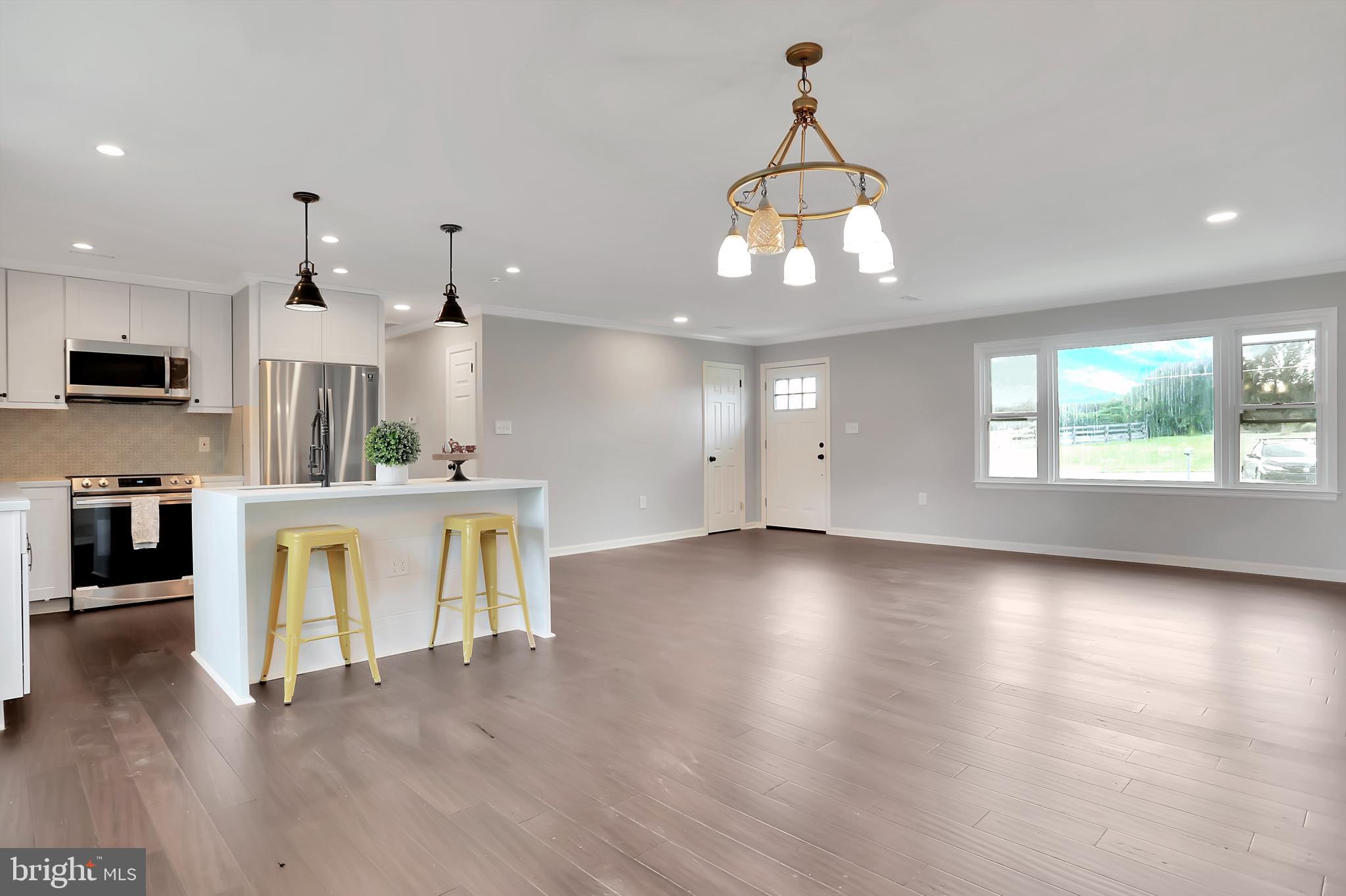 3192 Old Leetown Pike Ranson, WV 25438 - Photo 21 of 50 a view of a living room and kitchen with furniture wooden floor and chandelier