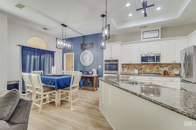 a kitchen with stainless steel appliances granite countertop a stove a sink a dining table and chairs with wooden floor