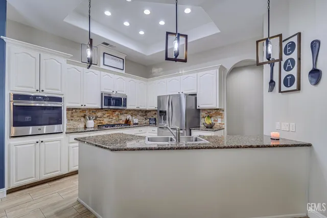 a kitchen with stainless steel appliances granite countertop a sink a stove and a refrigerator