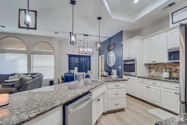 a kitchen with granite countertop a sink a counter space appliances and cabinets