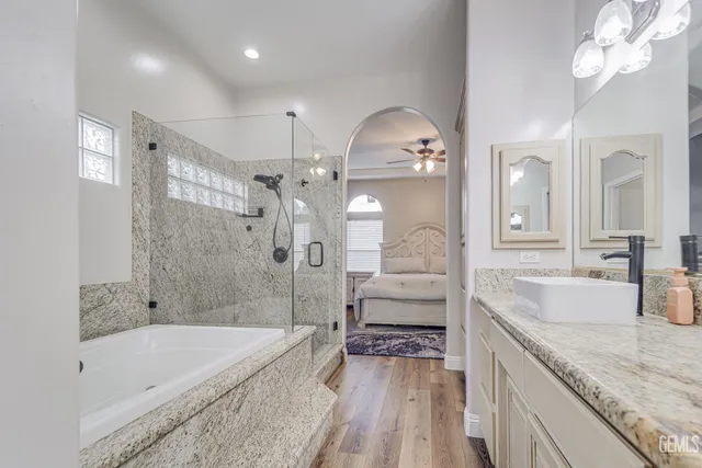 a spacious bathroom with a granite countertop tub a double vanity sink and a large mirror