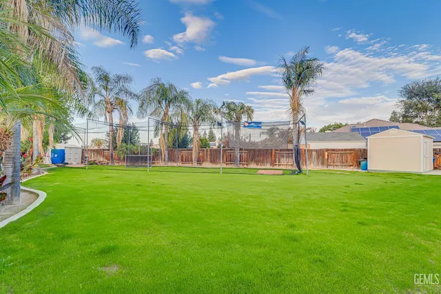 a view of a apartment with a big yard and large trees
