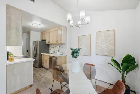 a white kitchen with stainless steel appliances a table and chairs in it