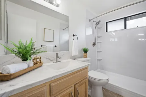 a bathroom with a granite countertop sink a toilet and shower