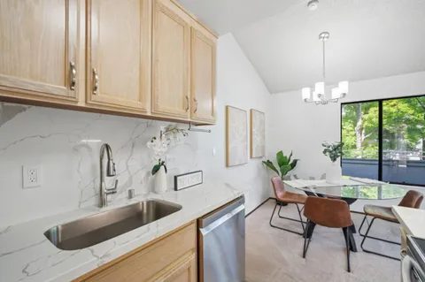 a kitchen with stainless steel appliances granite countertop a sink and white cabinets next to a window