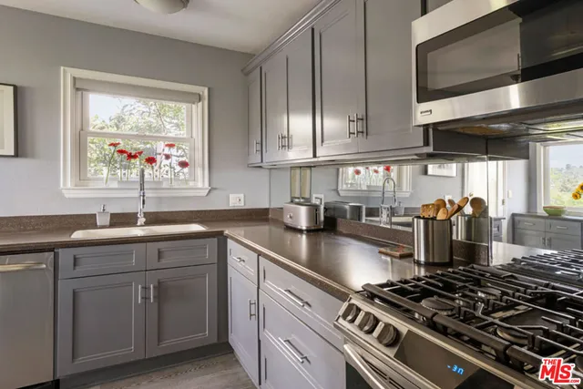 a kitchen with stainless steel appliances granite countertop a stove a sink dishwasher and cabinets with wooden floor