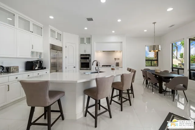 a kitchen with stainless steel appliances kitchen island granite countertop a dining table chairs and sink