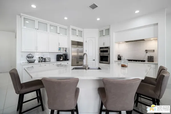 a kitchen with stainless steel appliances granite countertop a dining table chairs microwave and sink