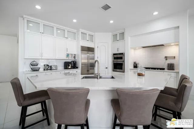 a kitchen with stainless steel appliances granite countertop a dining table chairs microwave and sink