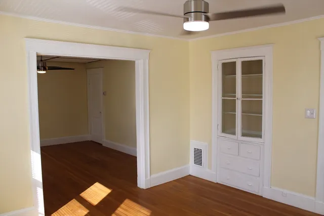 an empty room with wooden floor closet and windows