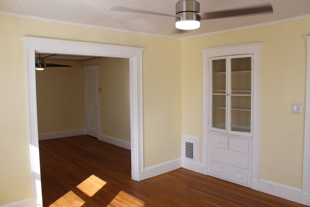 242 Newbury Avenue, Unit 2 Quincy, MA 02171 - Photo 3 of 6 an empty room with wooden floor closet and windows