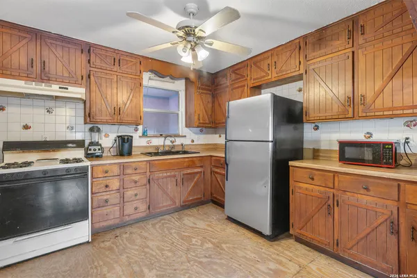 a kitchen with stainless steel appliances granite countertop a refrigerator a sink dishwasher a stove with wooden cabinets and floor