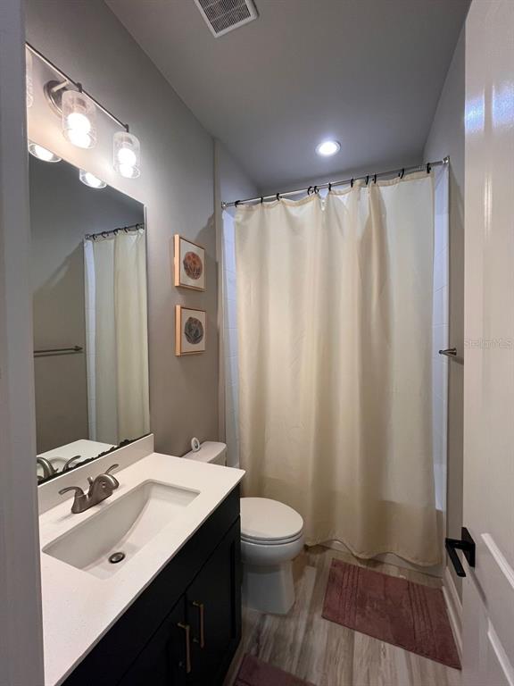 12149 Southwest 33rd Place Gainesville, FL 32608 - Photo 25 of 35 a bathroom with a sink a toilet a mirror and shower curtain