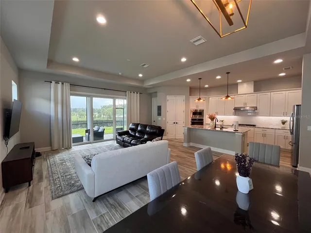 a large living room with stainless steel appliances furniture and a large window