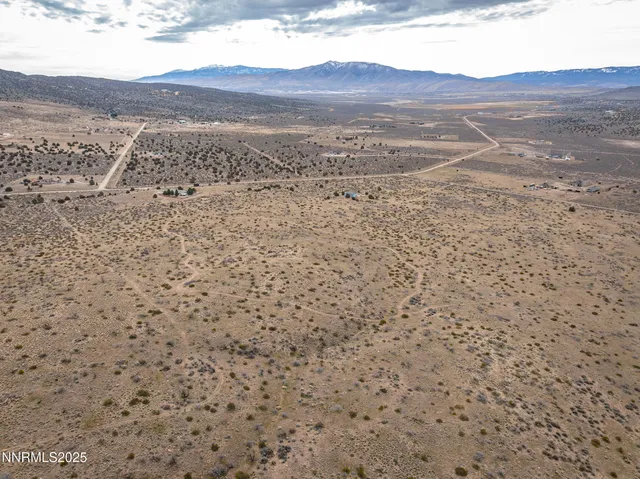a view of a dry field with mountains in the background