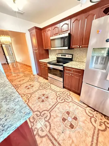 a kitchen with stainless steel appliances granite countertop a refrigerator sink and stove