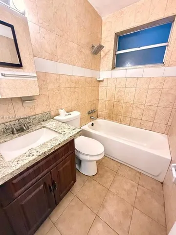 a bathroom with a granite countertop sink a toilet and bathtub