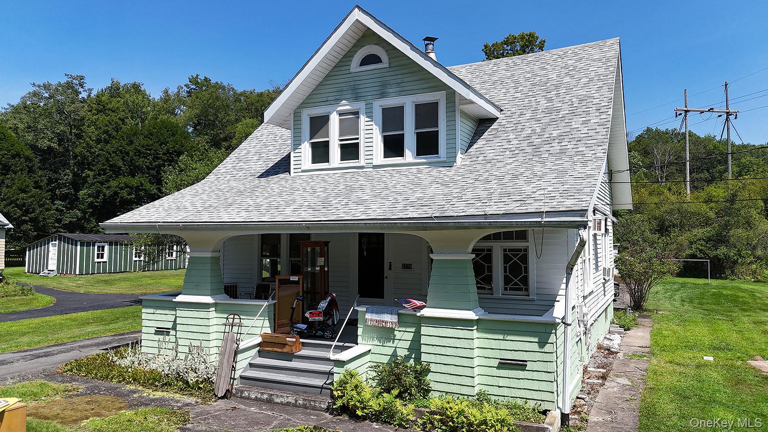 1779 Shandelee Road Livingston Manor, NY 12758 - Photo 27 of 31 View of front of home featuring a porch, a front lawn, a shingled roof, and an outbuilding