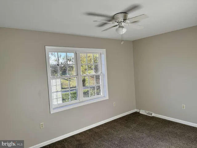 an empty room with a window and a fan