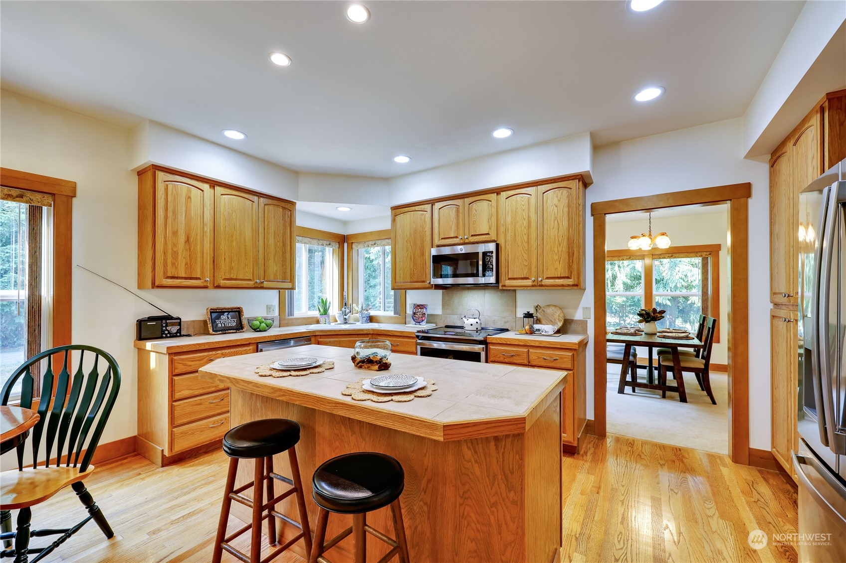 5701 Northeast Gunderson Road Poulsbo, WA 98370 - Photo 25 of 40 a kitchen with a stove a sink a kitchen island with chairs and wooden floor