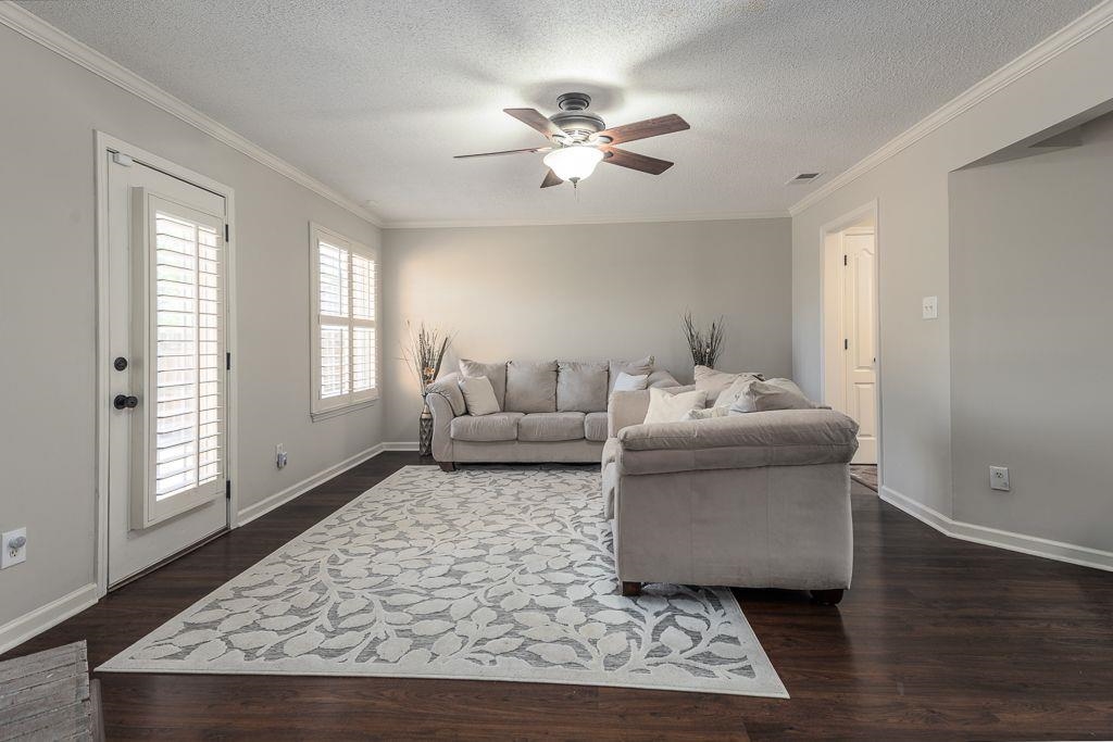 9768 Riggin Drive Memphis, TN 38002 - Photo 15 of 32 Spacious living area featuring dark wood-finish flooring, light gray wall paint, and white crown molding