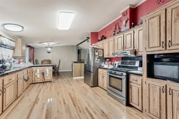 a kitchen with stainless steel appliances granite countertop a lot of counter top space and wooden floor