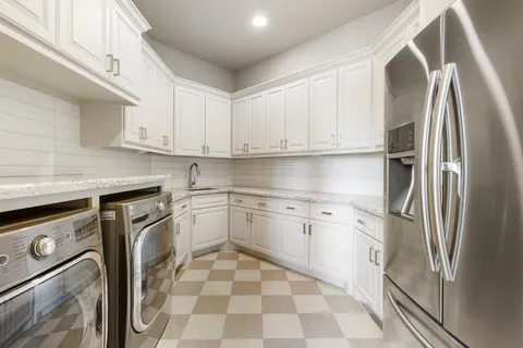 a kitchen with stainless steel appliances granite countertop a refrigerator sink and white cabinets