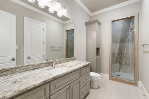 a bathroom with a granite countertop sink a toilet and shower