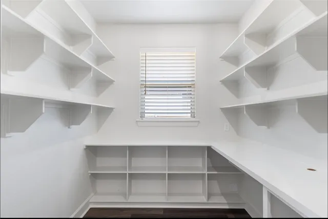 a kitchen with white cabinets and window