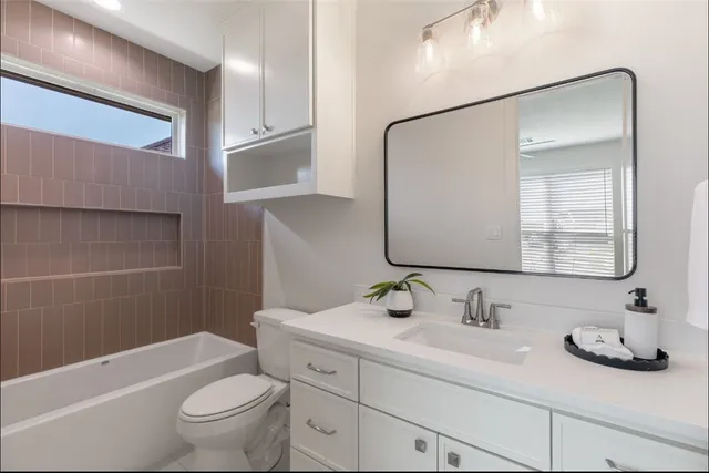 a bathroom with a granite countertop sink a toilet a mirror and bathtub