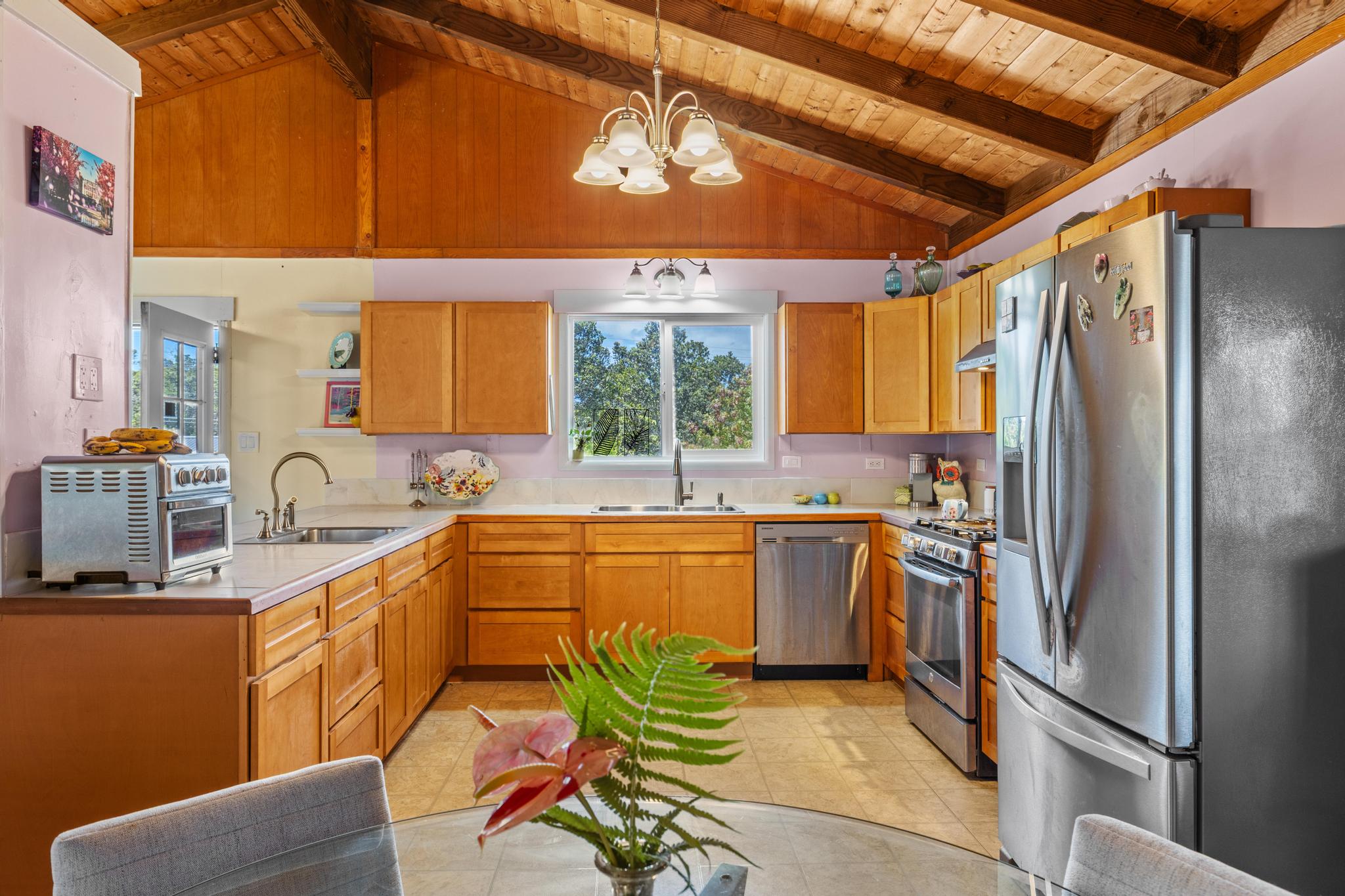 11-3681 Old Volcano Road Volcano, HI 96785 - Photo 6 of 26 a kitchen with stainless steel appliances kitchen island granite countertop a refrigerator a sink dishwasher a stove and white countertops with wooden floor