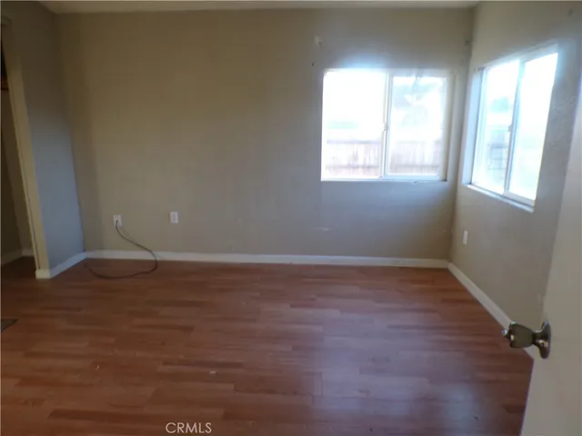 a view of an empty room with wooden floor and cabinet