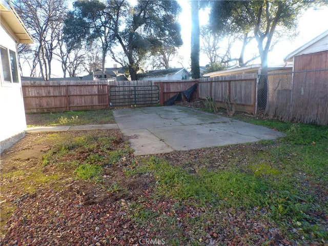 a view of backyard with wooden fence and large trees