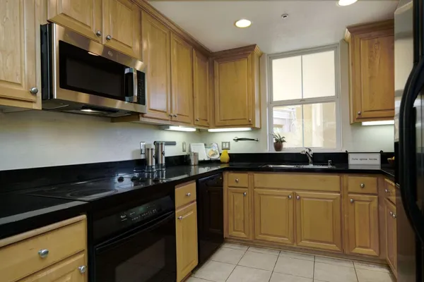 a kitchen with stainless steel appliances granite countertop a sink a stove a microwave and wooden cabinets