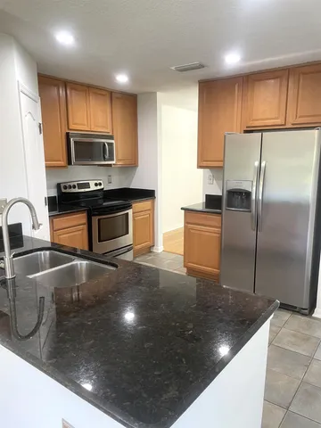 a kitchen with stainless steel appliances granite countertop a sink a stove a refrigerator a washer dryer and white cabinets