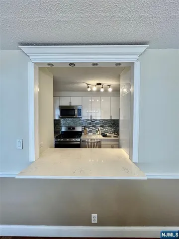 a view of a kitchen with kitchen island a sink stainless steel appliances and cabinets