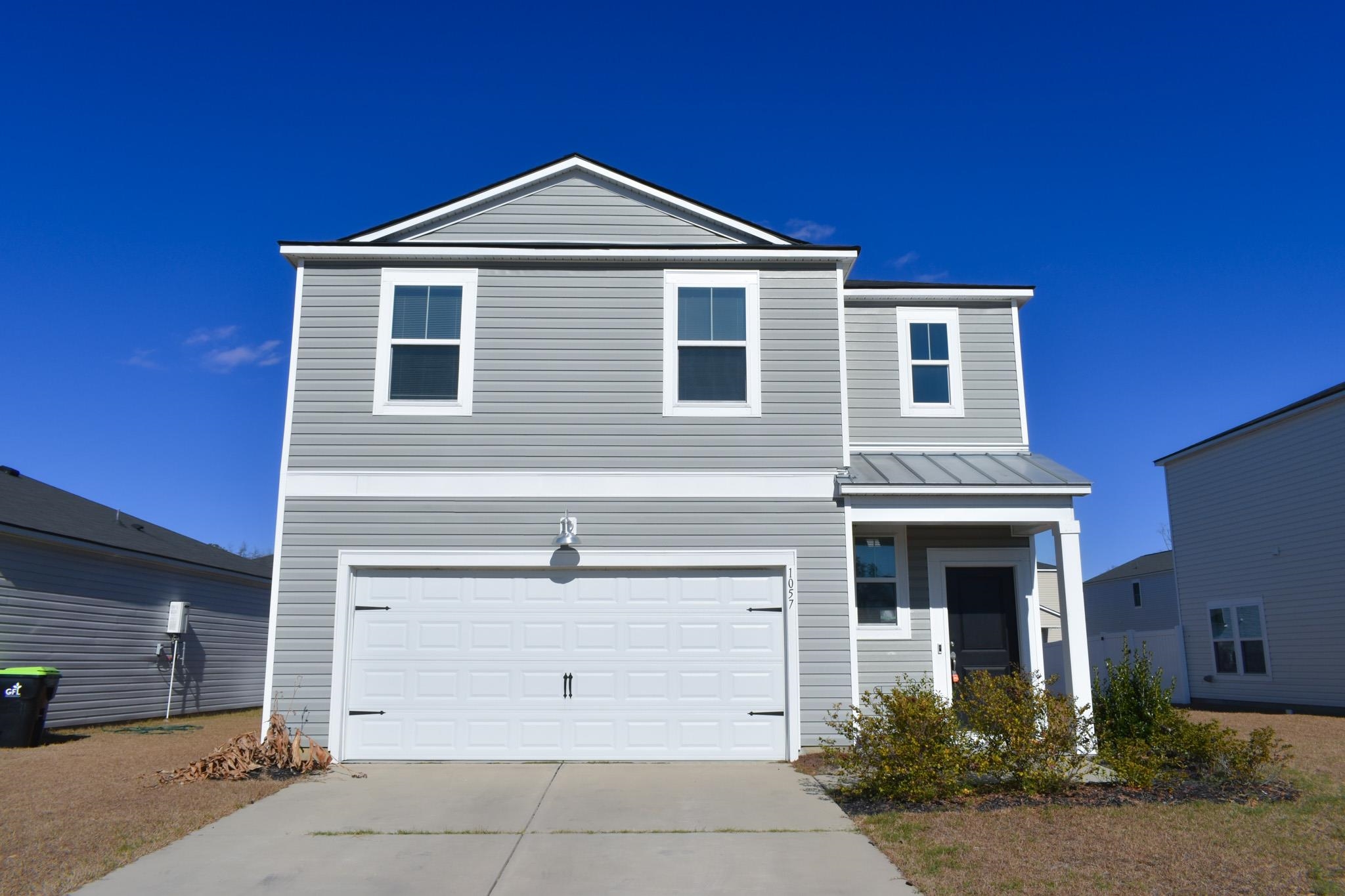 Traditional-style home featuring driveway, a standing seam roof, a garage, and a metal roof