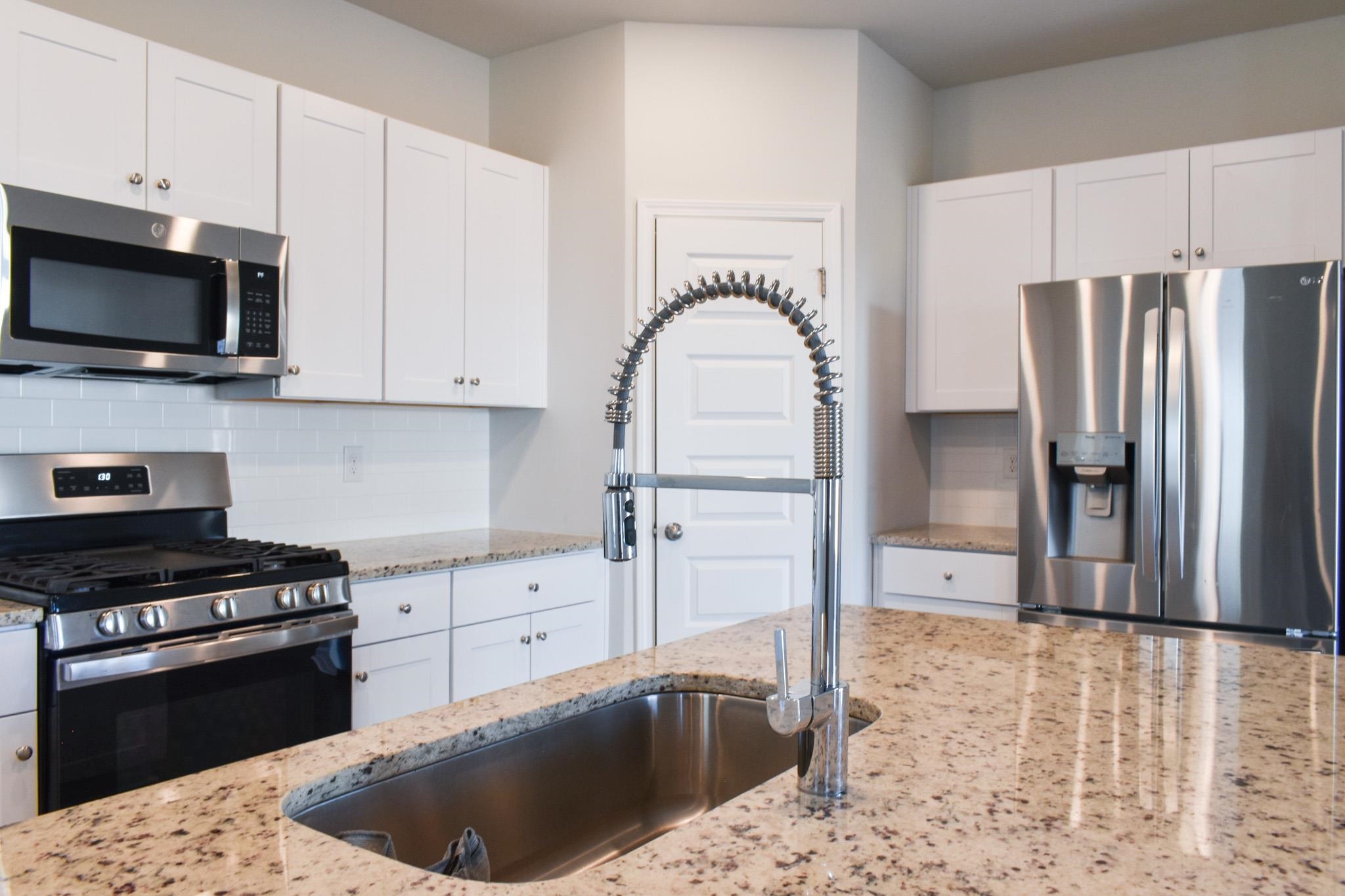 1057 Saltgrass Way Myrtle Beach, SC 29588 - Photo 2 of 23 Kitchen featuring stainless steel appliances, white cabinets, backsplash, and light stone countertops