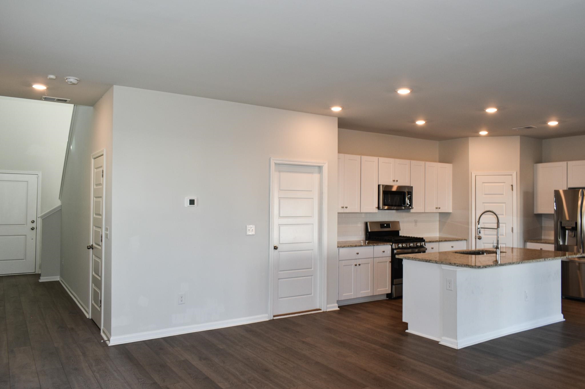 1057 Saltgrass Way Myrtle Beach, SC 29588 - Photo 6 of 23 Kitchen with appliances with stainless steel finishes, white cabinetry, dark stone counters, recessed lighting, and a center island with sink
