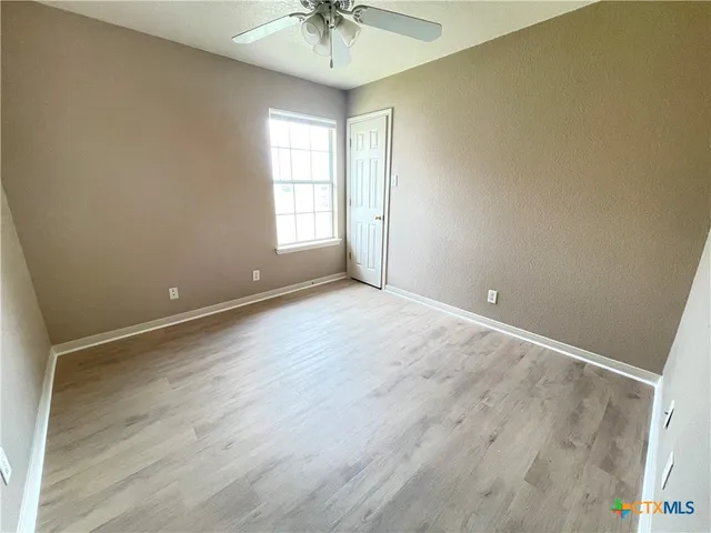 an empty room with a chandelier fan and windows