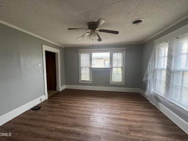 a view of empty room with wooden floor and fan