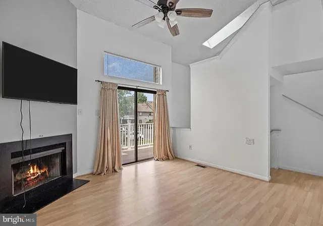 a view of an empty room with wooden floor fireplace and a window