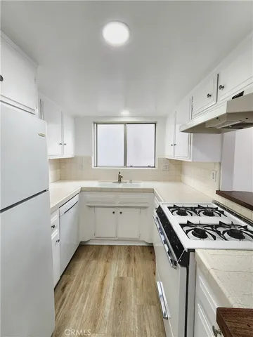 a kitchen with cabinets appliances a sink and a window