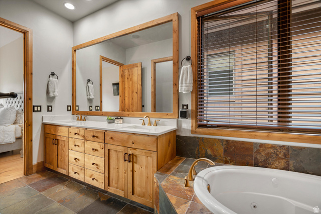 4892 Eagle Rdg Drive Eden, UT 84310 - Photo 21 of 39 Dual sink vanity with wood cabinetry and white countertops, a large framed mirror, recessed lighting, and a window with wood blinds