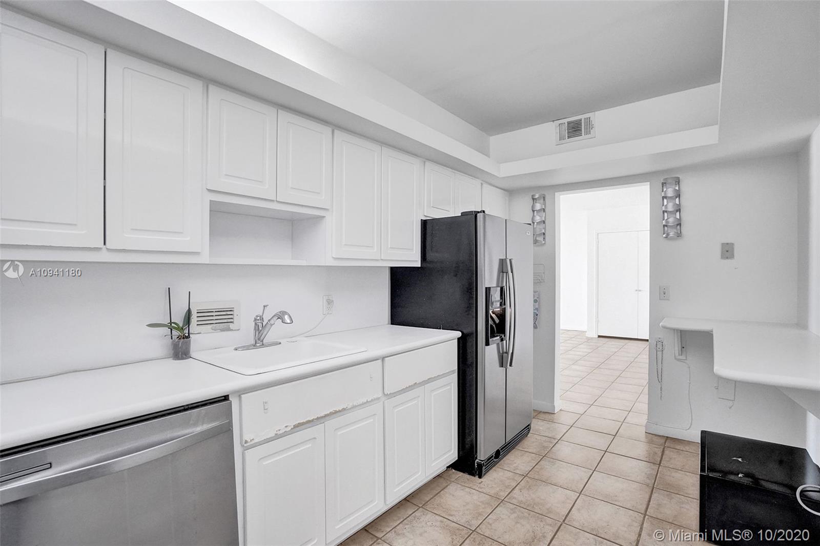 10185 Collins Avenue, Unit 818 Bal Harbour, FL 33154 - Photo 9 of 41 a kitchen with a sink a refrigerator and cabinets