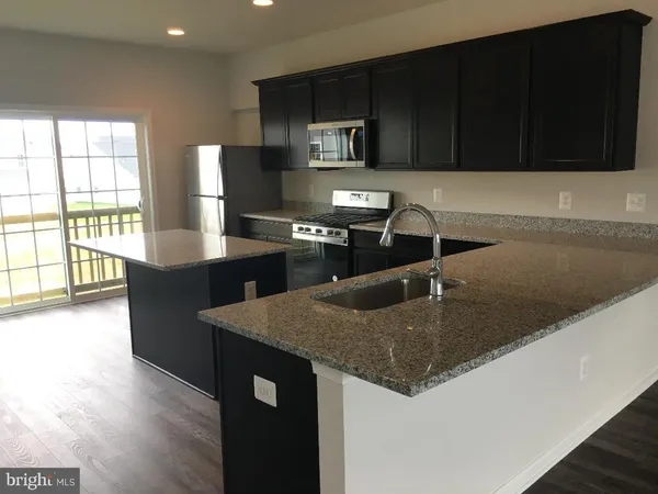 a kitchen with granite countertop a stove a sink and a microwave