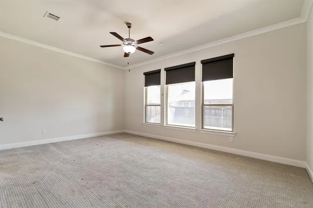 an empty room with chandelier fan and windows