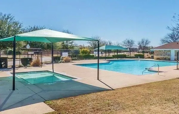 a swimming pool with lawn chairs under an umbrella